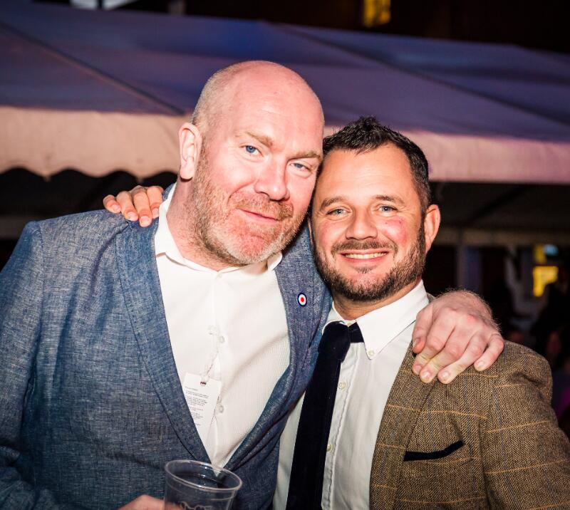 Two gents in suits posing for a picture at the races