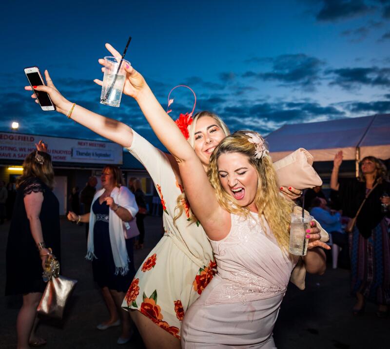 Two race goers throwing out their best dance moves at a music event at Sedgefield Races